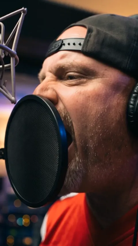 Richard performing into a pop-filtered microphone while recording Monarch of Madness